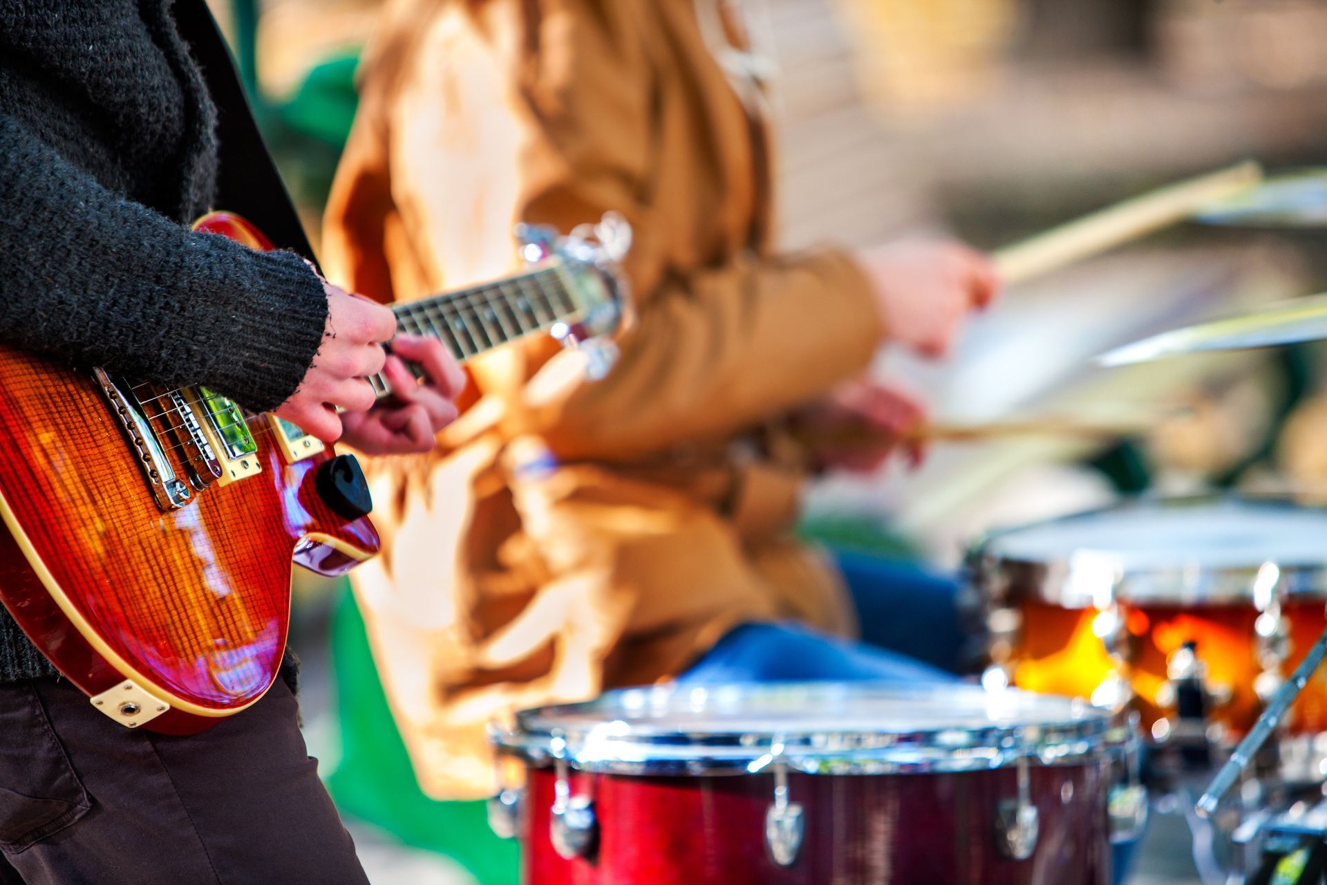 A man is playing a guitar and a woman is playing drums.