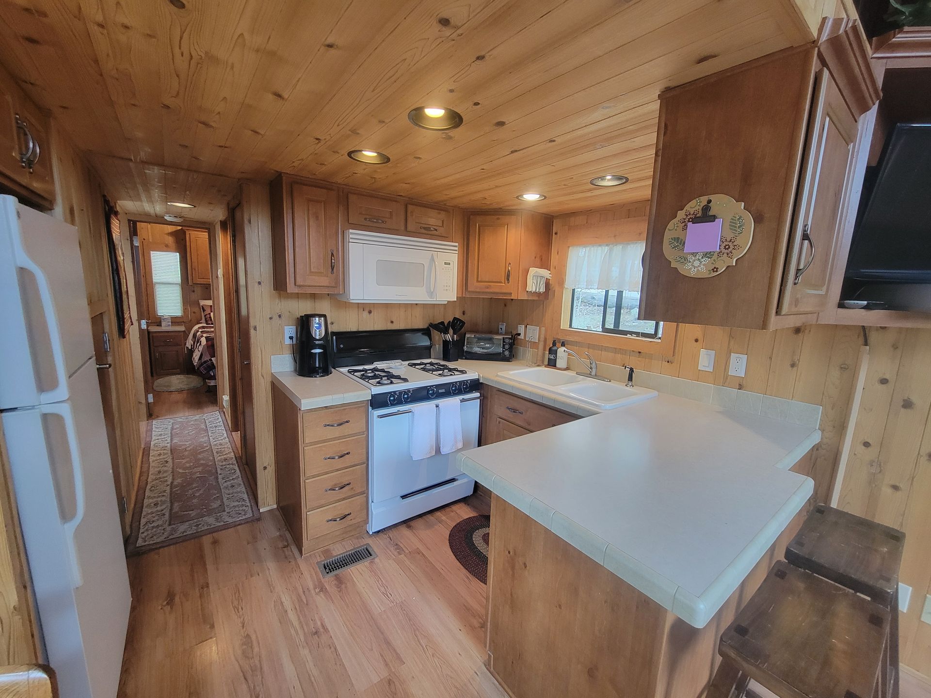 A kitchen with wooden cabinets , a stove , a refrigerator , and a microwave.