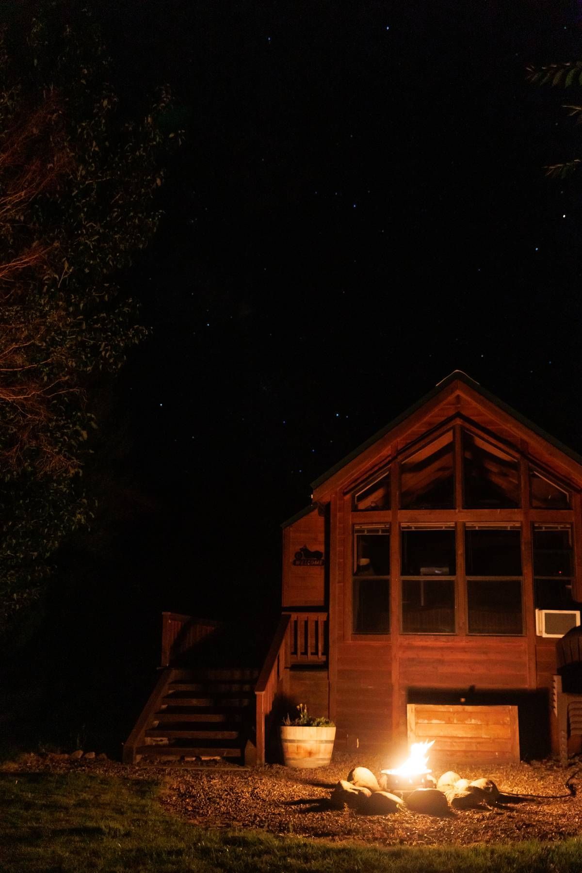 A cabin with a fire pit in front of it at night.