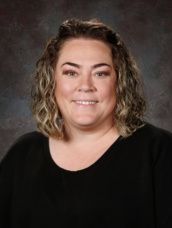 A woman in a floral shirt is smiling for a picture.