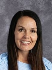 A woman in a blue shirt is smiling for the camera.