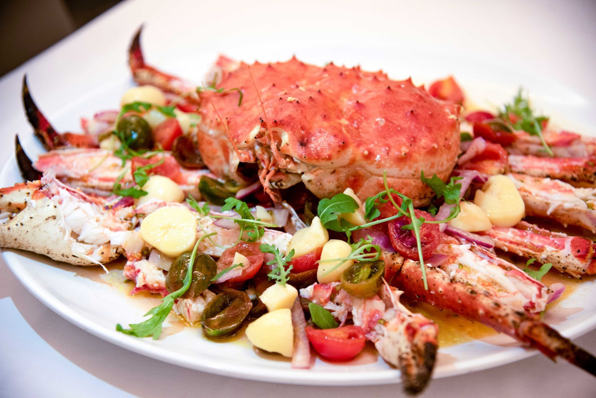 Piatto di granchio cotto con pomodori, patate ed erbe aromatiche.