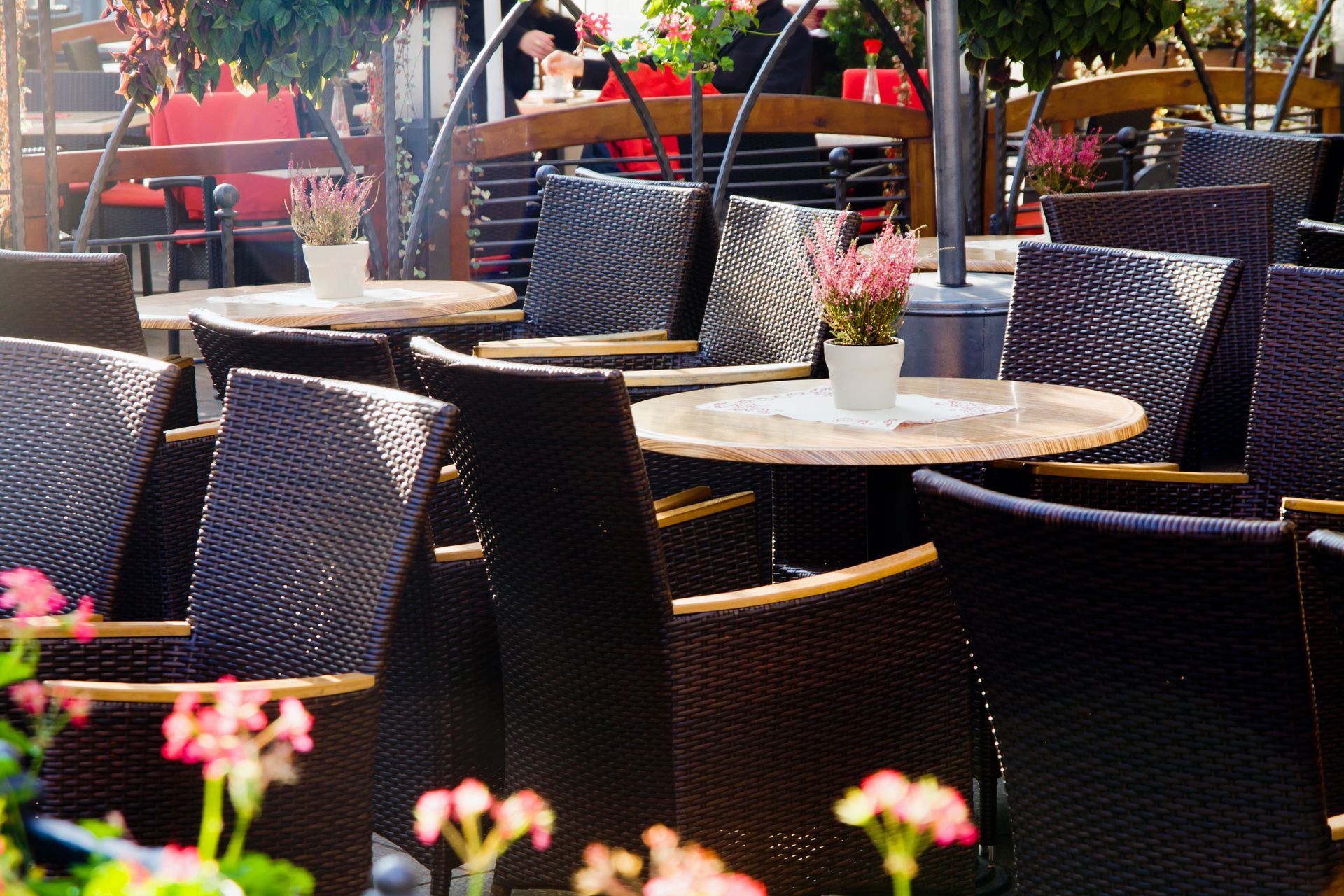Posti a sedere all'aperto del ristorante con sedie in vimini e tavolini rotondi, decorati con fiori.
