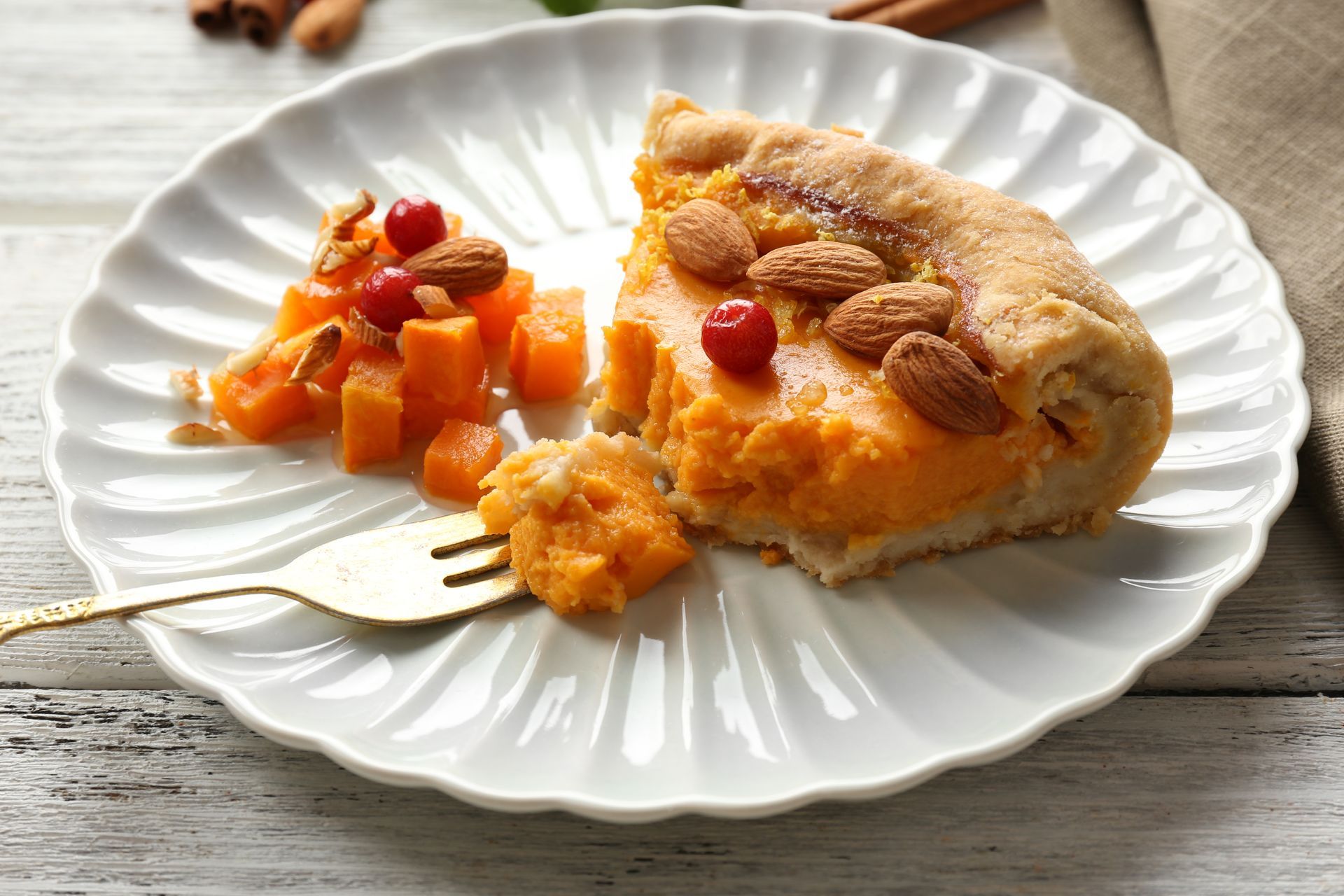 Fetta di galette di patate dolci con contorno di patate dolci a dadini e mandorle su un piatto bianco.