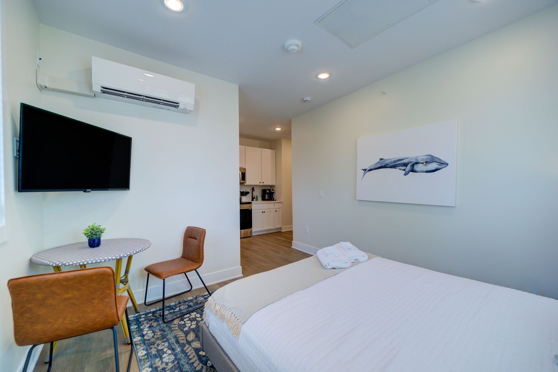 A bedroom with a bed , table , chairs , television and air conditioner.