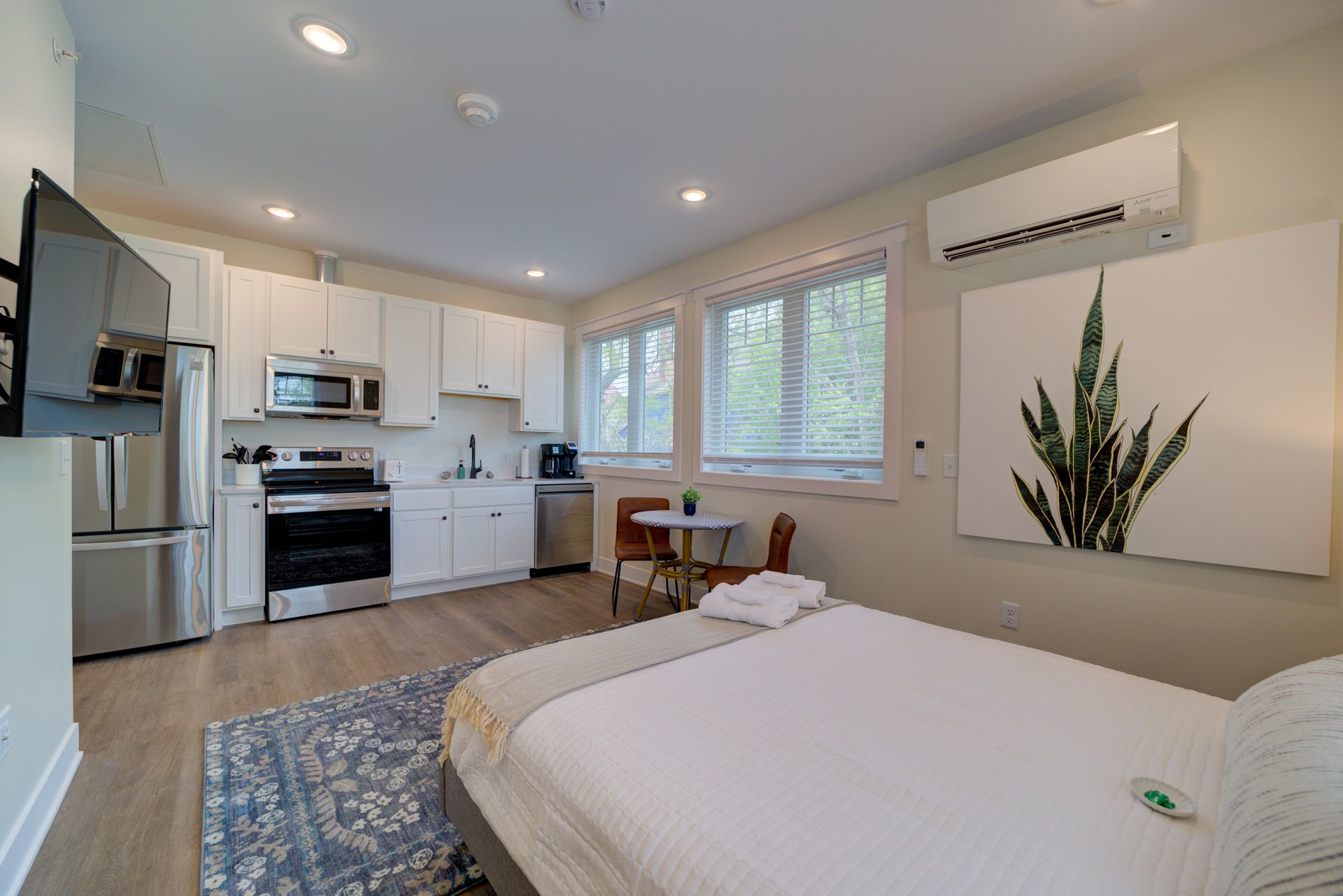 A bedroom with a bed , kitchen , and television.