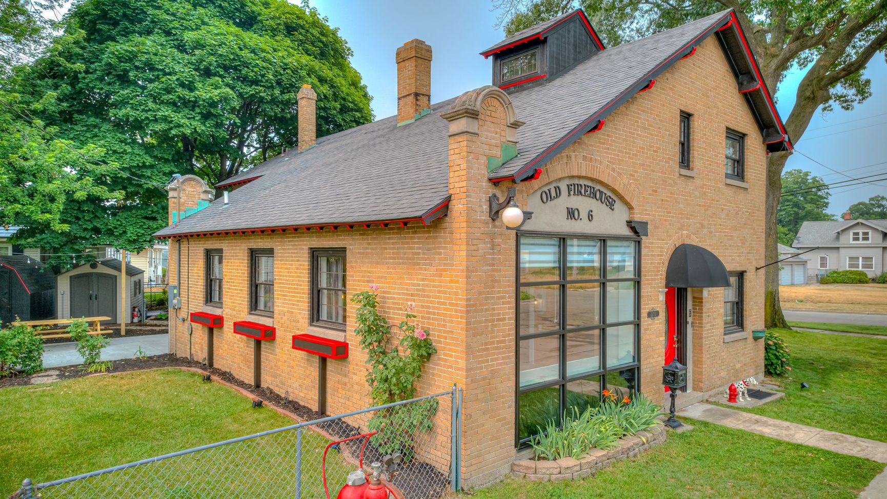 A brick building with a red door and a fence in front of it.