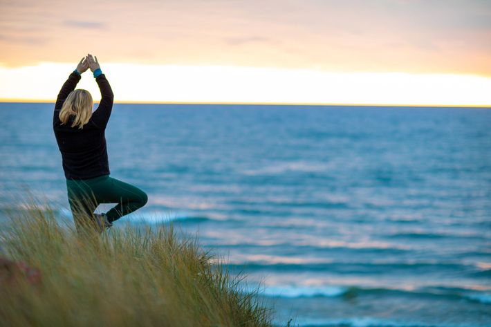 A table with plates , candles , and a bottle of wine on the beach.