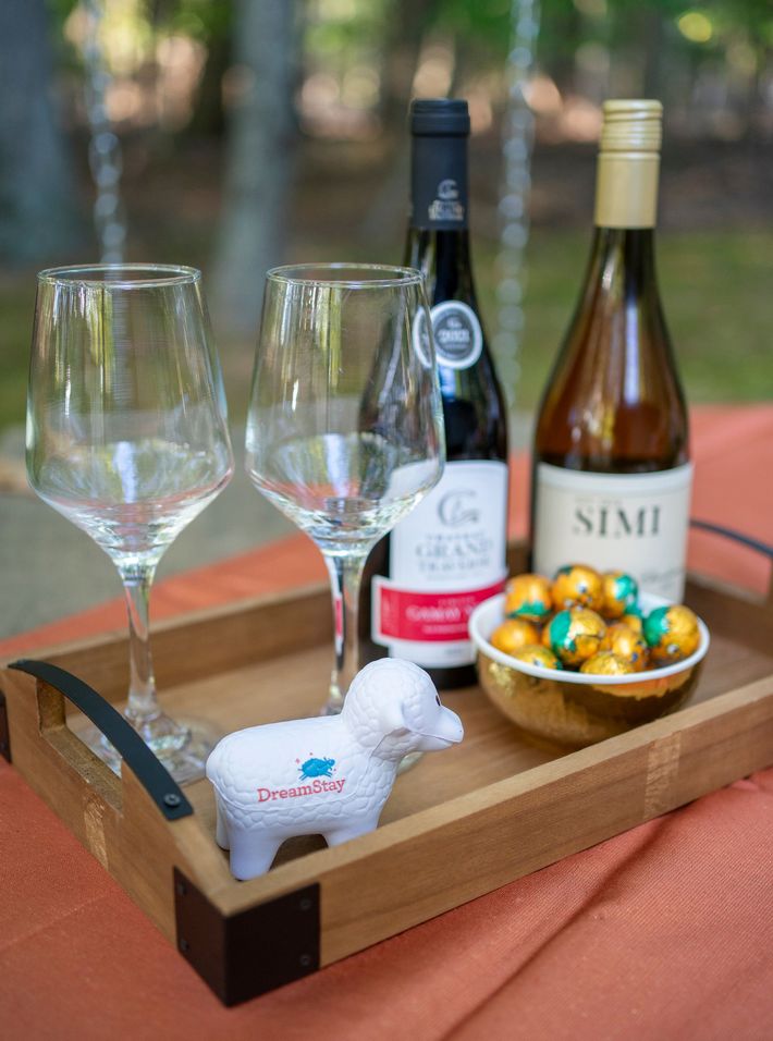 A wooden tray with wine bottles and glasses on it