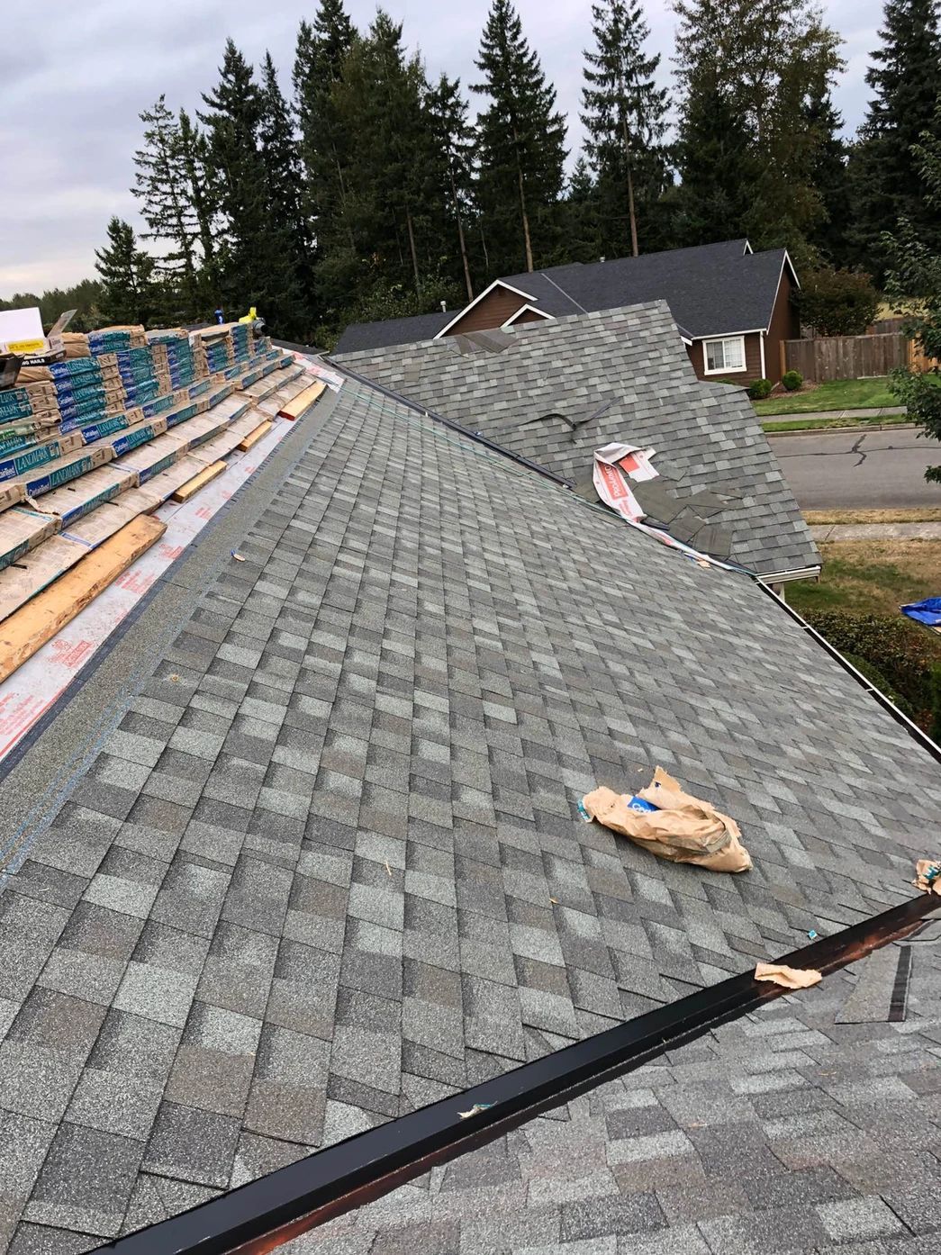 A roof is being installed on a house with a lot of shingles on it.