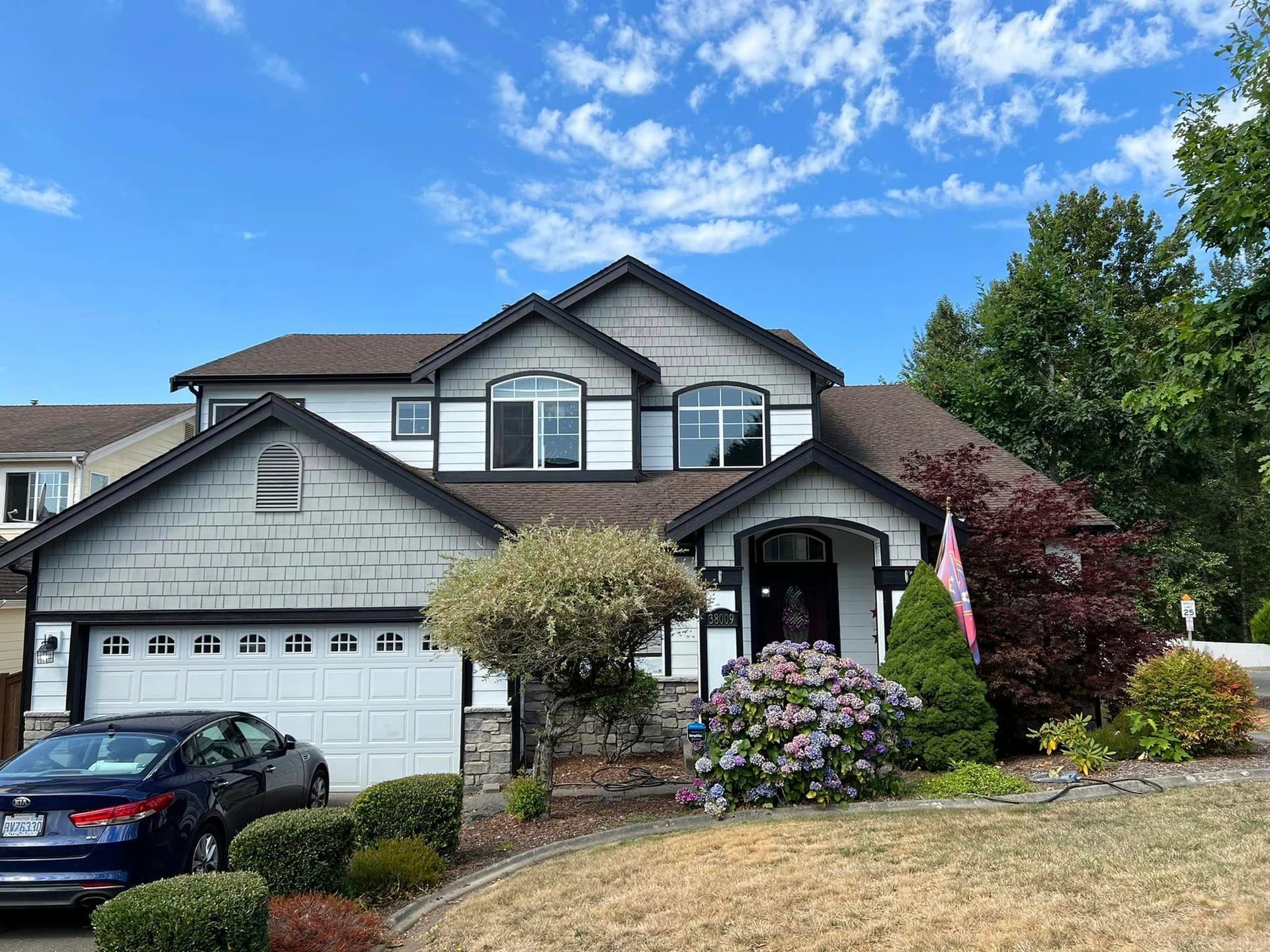 A large house with a car parked in front of it on a sunny day.