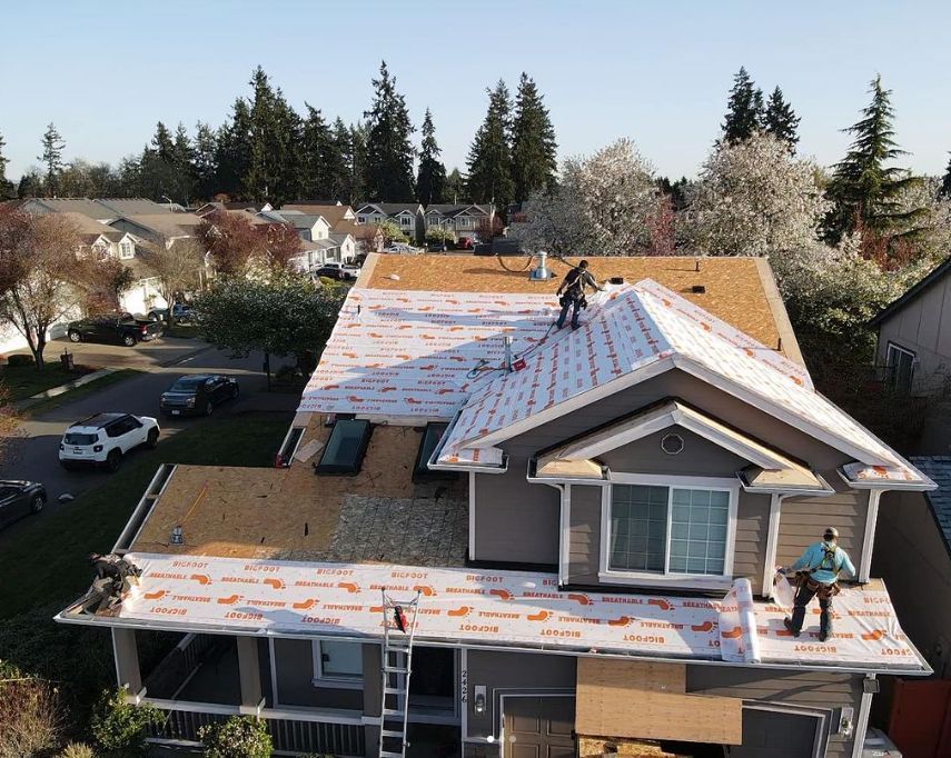 An aerial view of a house under construction with workers on the roof