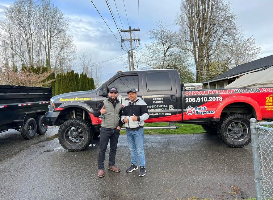 Two men are standing in front of a red truck.