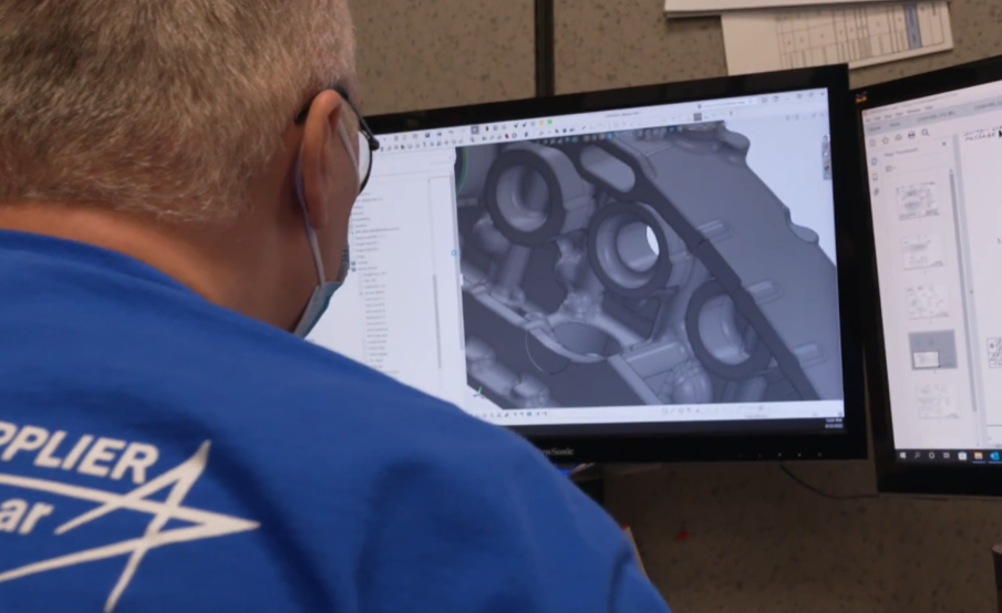 A man in a blue shirt is looking at a computer screen