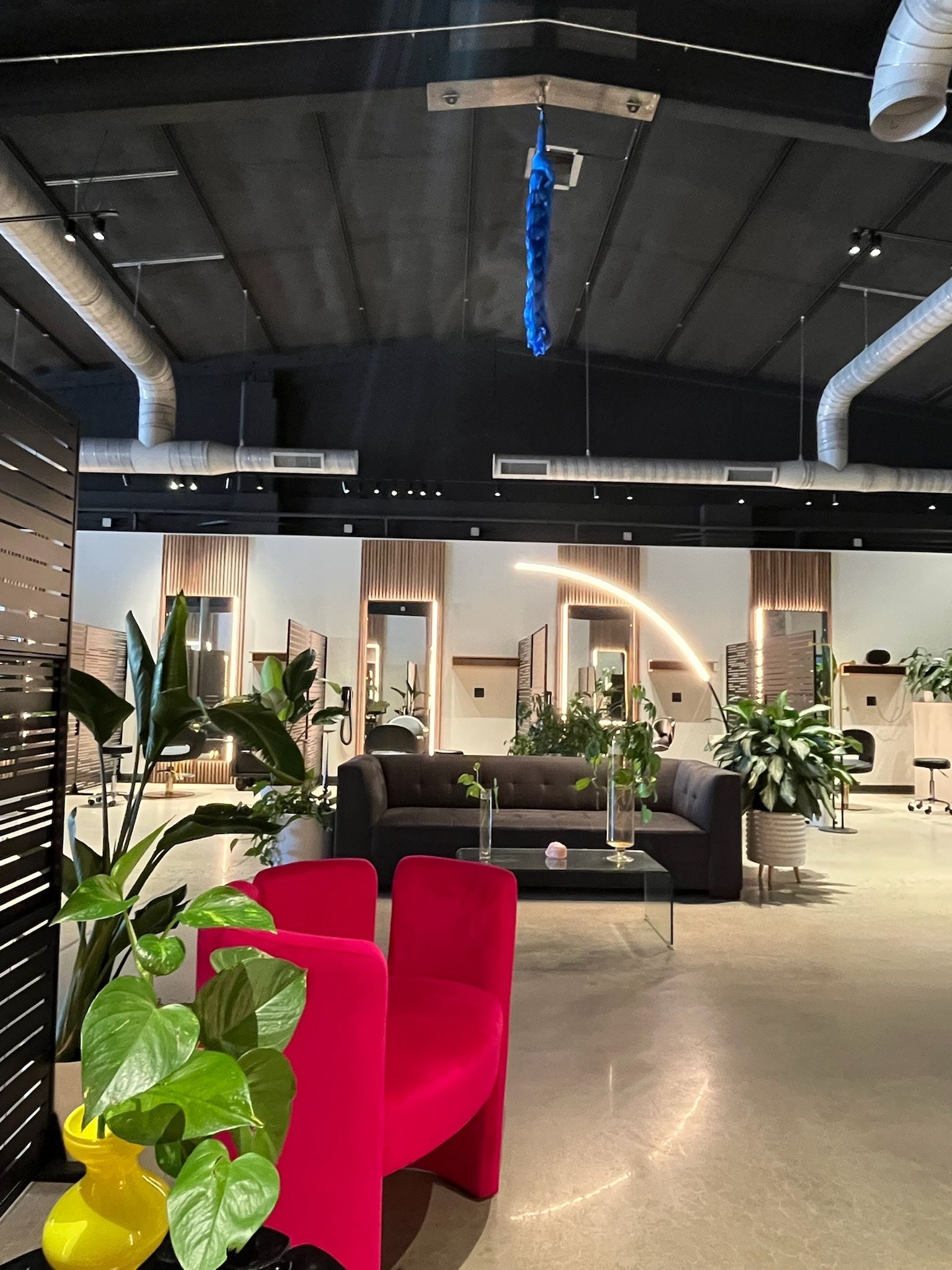 Red chairs and greenery in an interior with windows and dark ceiling.