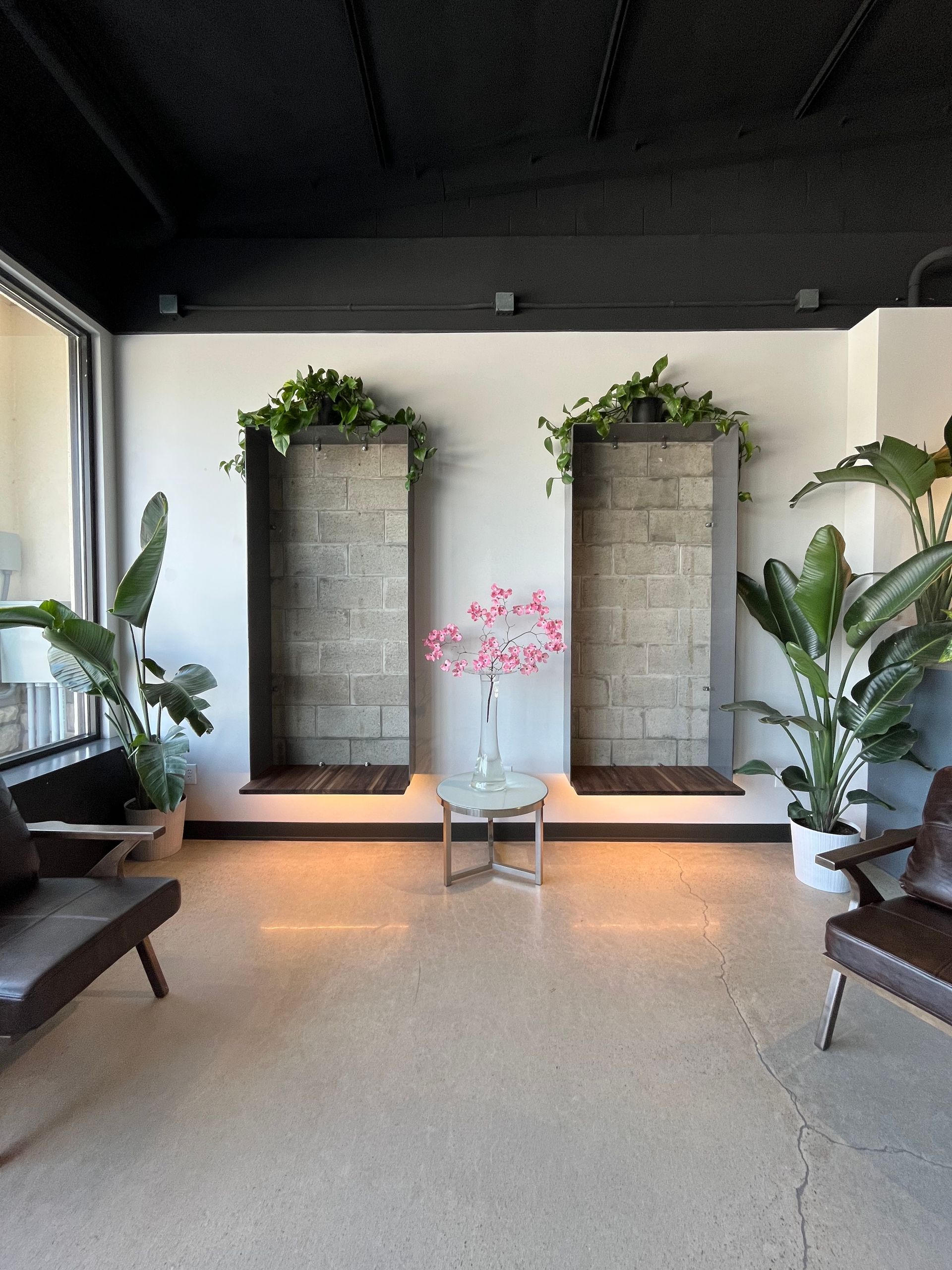 Black hair dryer on white table with beauty products and decor.