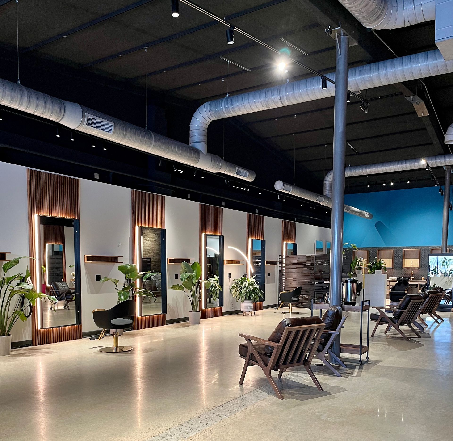 Hair salon interior with black slatted dividers, plants, and a stylist chair.