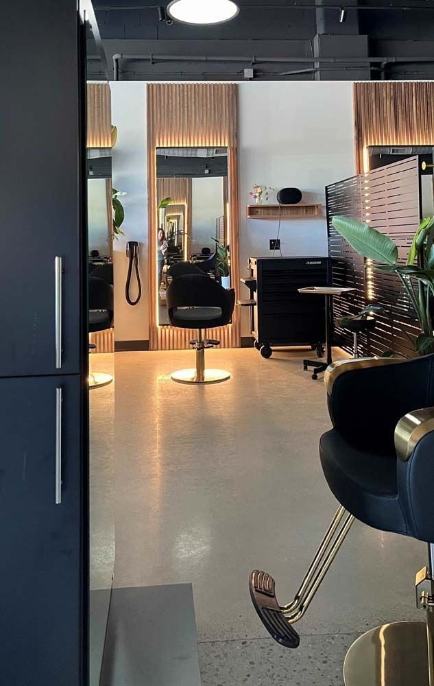 Hair salon interior with mirrors, black chairs, and wood accents.