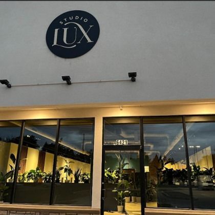 Studio LUX storefront with dark blue sign and large windows displaying plants.