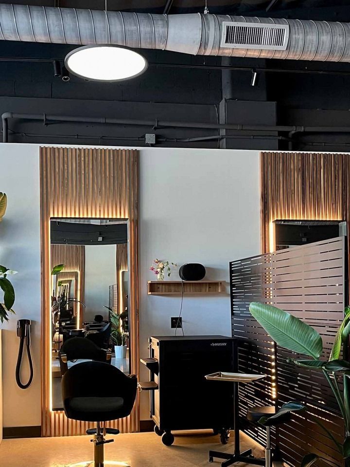 Hair salon interior with mirrors, styling chair, and black cart.