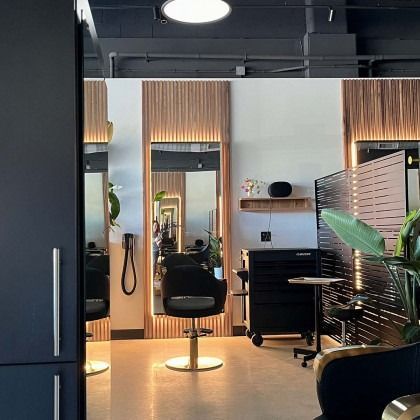 Interior of a hair salon with mirrors, black chairs, and gold accents.