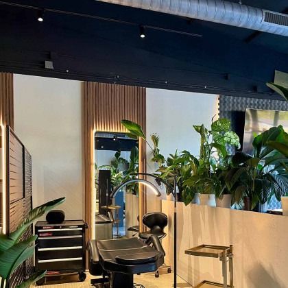 Stylish interior with tattoo chair, plants, mirror, and black accents.