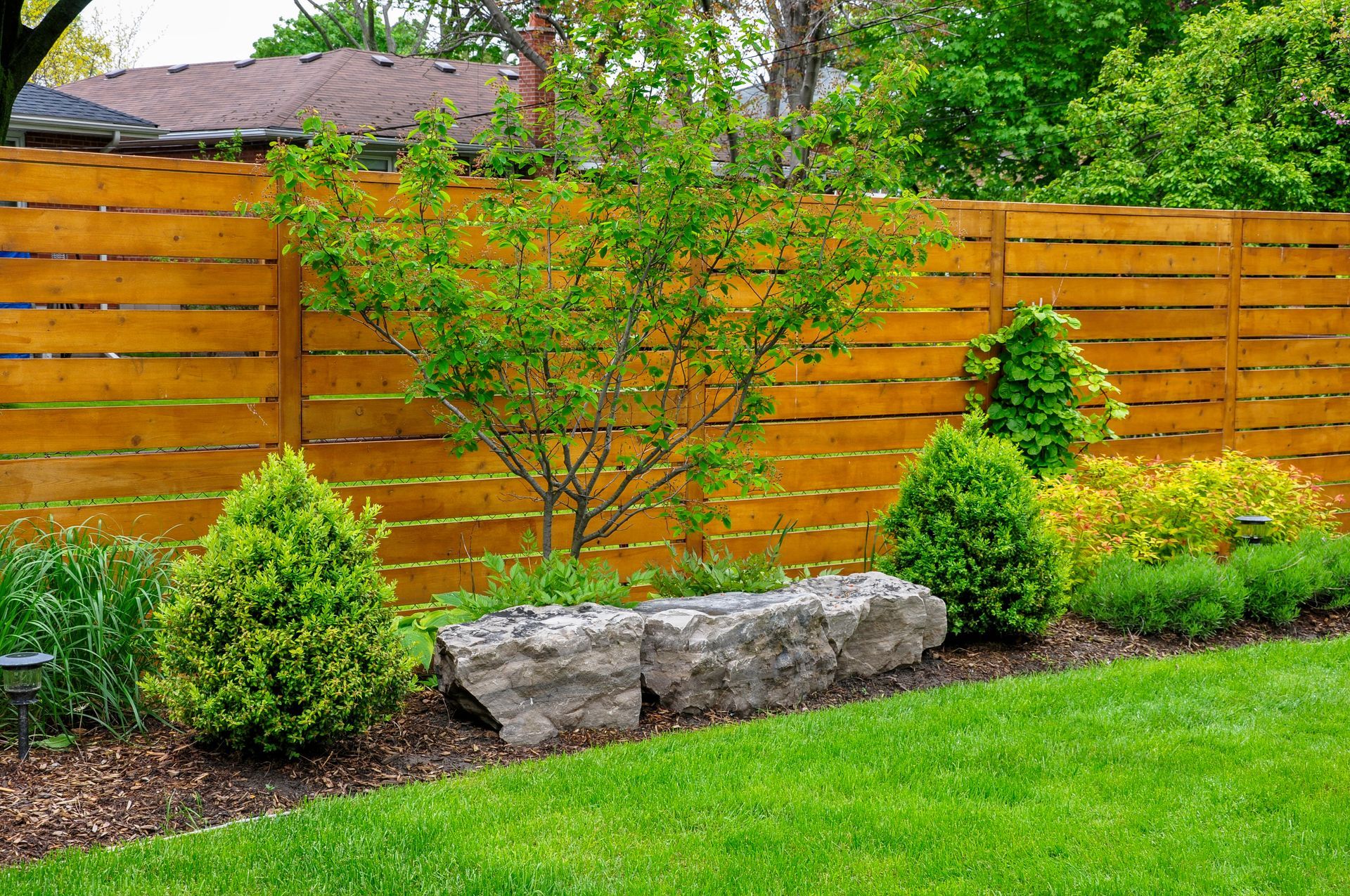 a wooden fence surrounds a lush green lawn in a backyard .