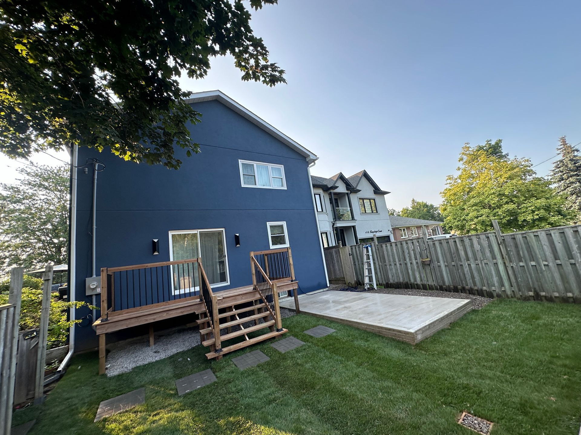 A blue house with a deck and stairs in the backyard