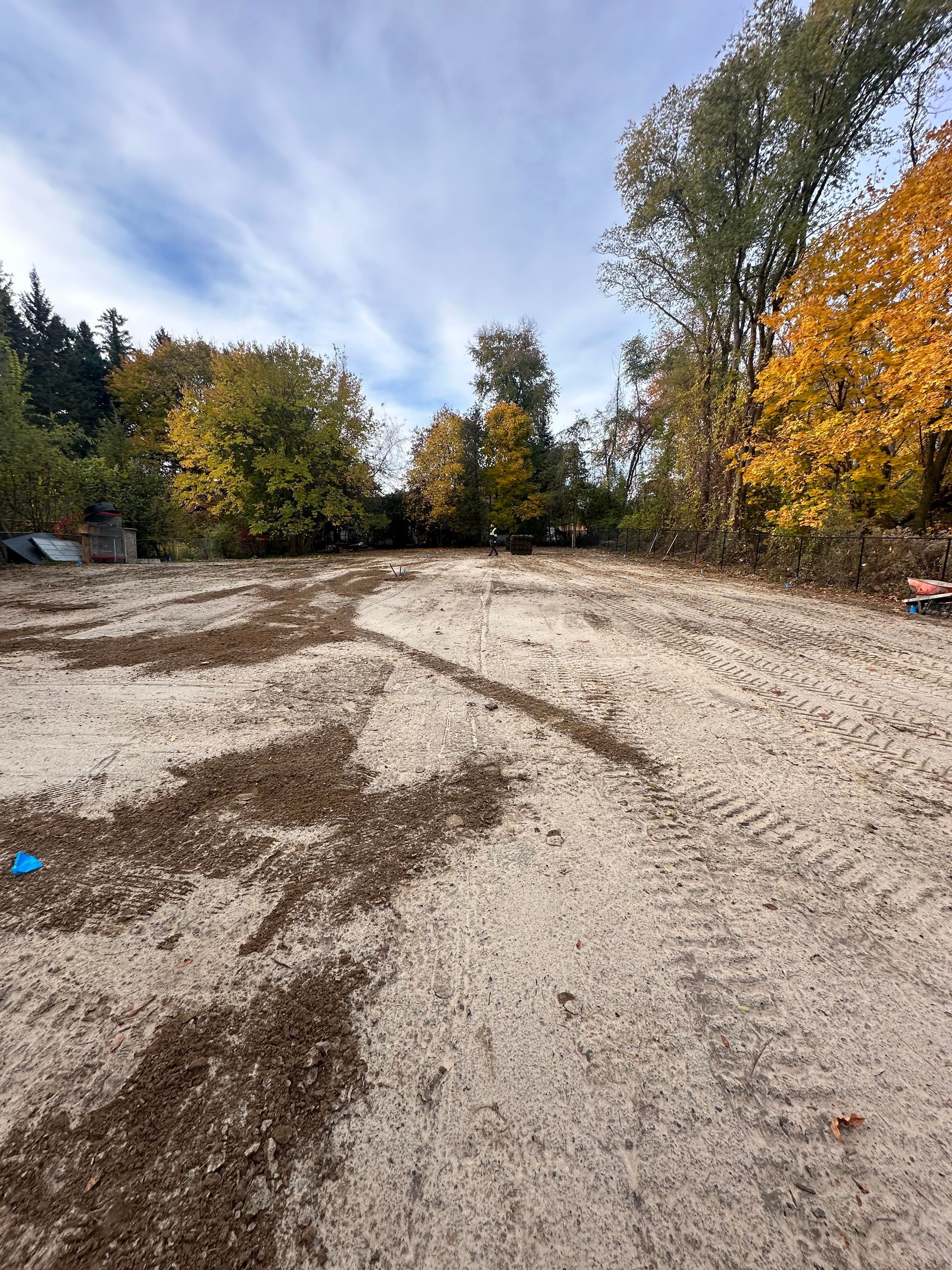 a large dirt field with trees in the background on a sunny day .