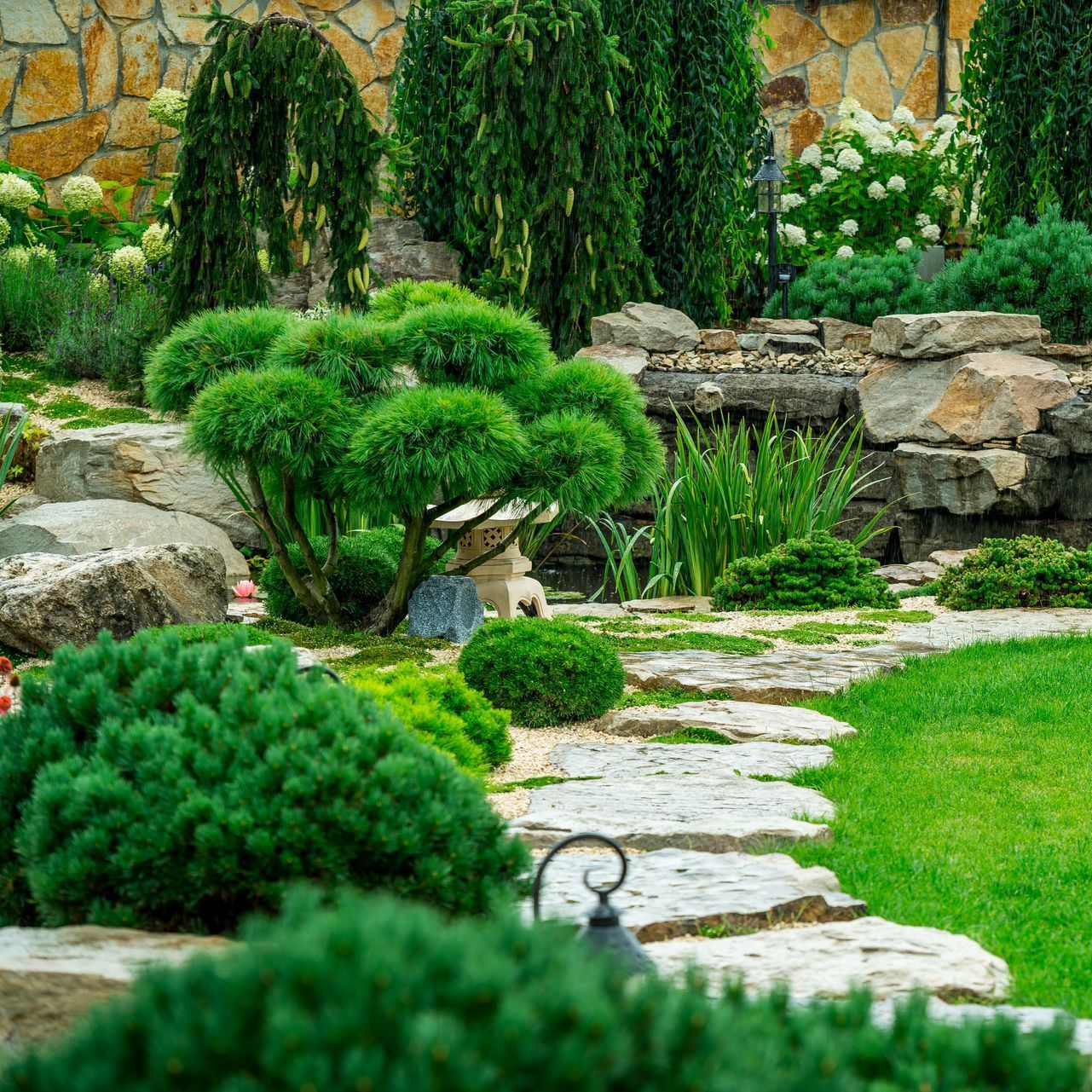 a stone path in a garden surrounded by trees and bushes .