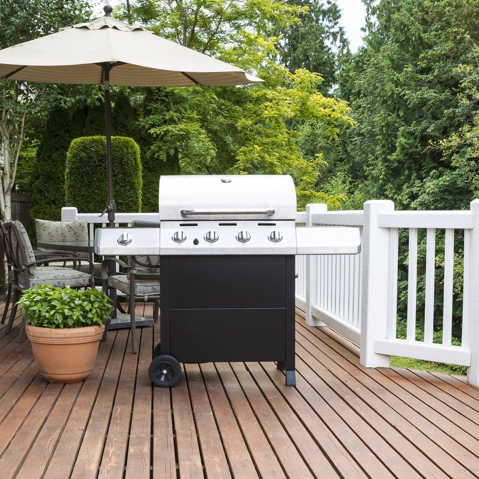 a grill is sitting on a wooden deck under an umbrella