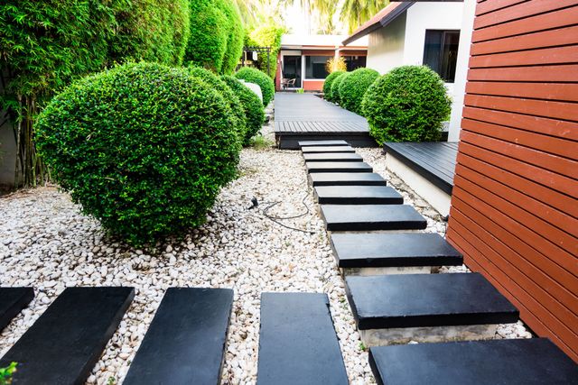 a row of black steps leading to a house in a garden .