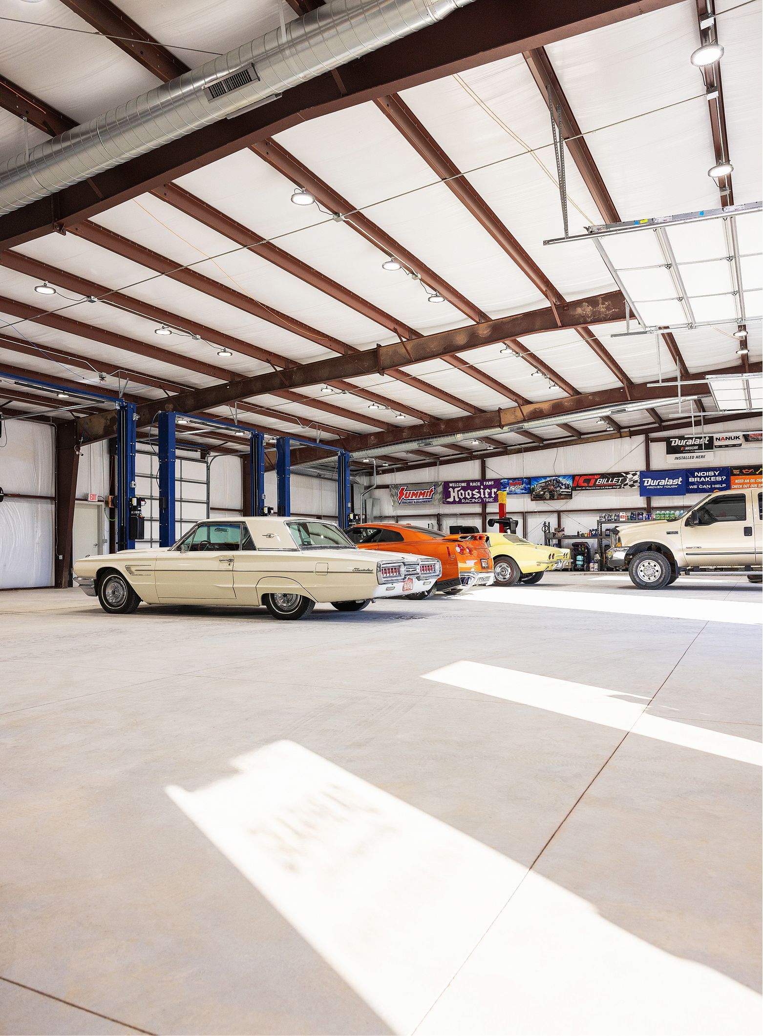 Classic cars inside a bright garage, including a light beige convertible. | Gearhead Autoworks
