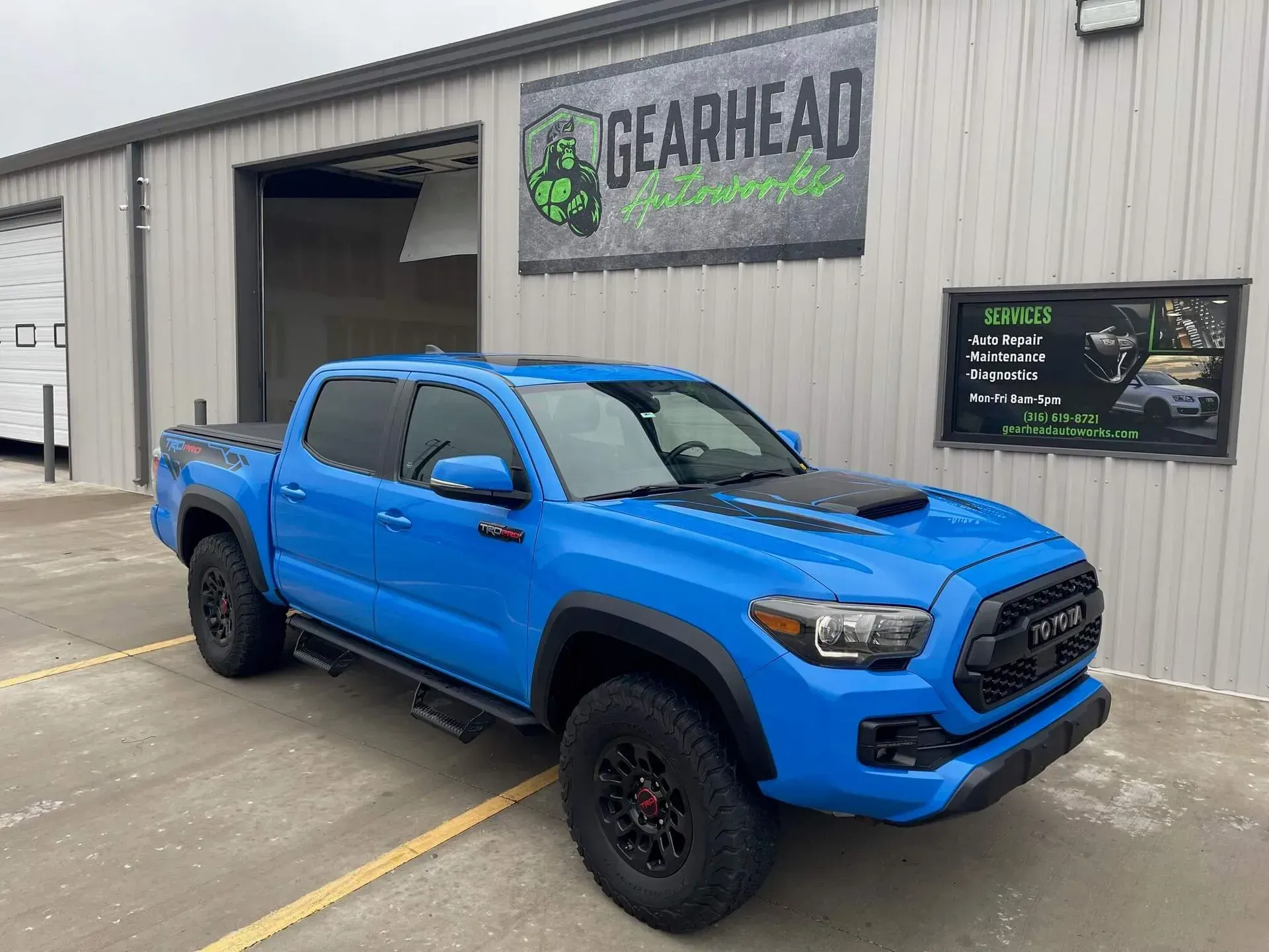 Bright blue Toyota Tacoma truck parked in front of a Gearhead Automotive shop. | Gearhead Autoworks