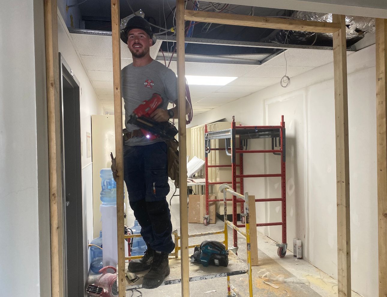 A man is standing on a wooden frame in a room.