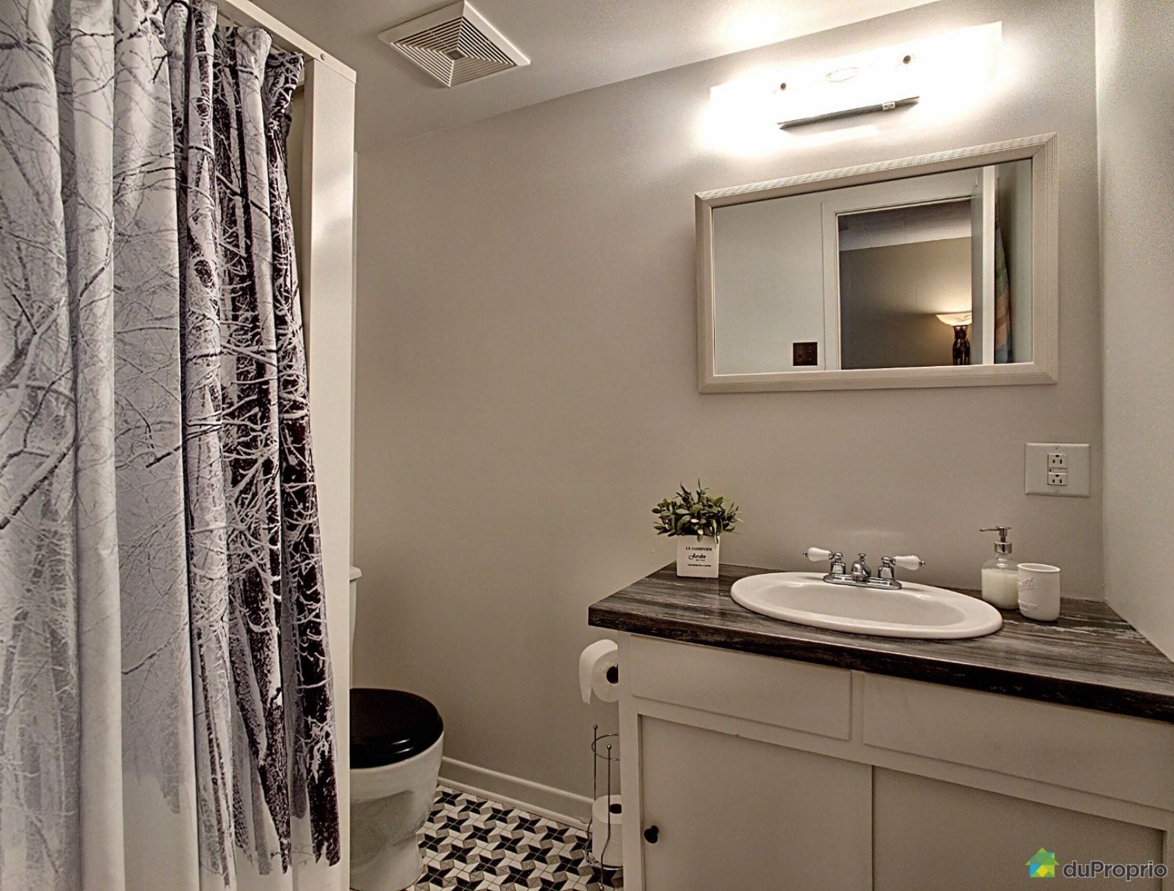 A bathroom with a sink , toilet , mirror and shower curtain.