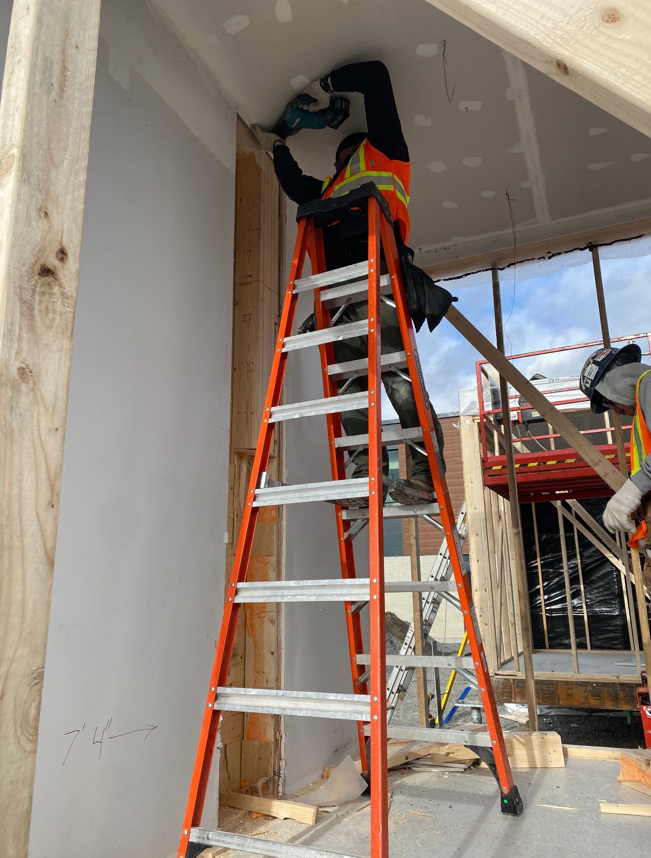 A man is standing on a ladder working on a ceiling