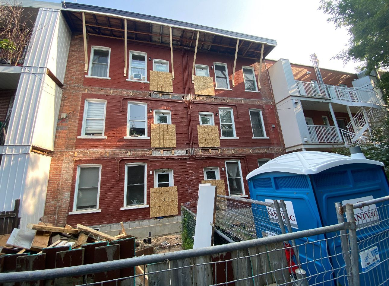 A large brick building with a blue portable toilet in front of it.