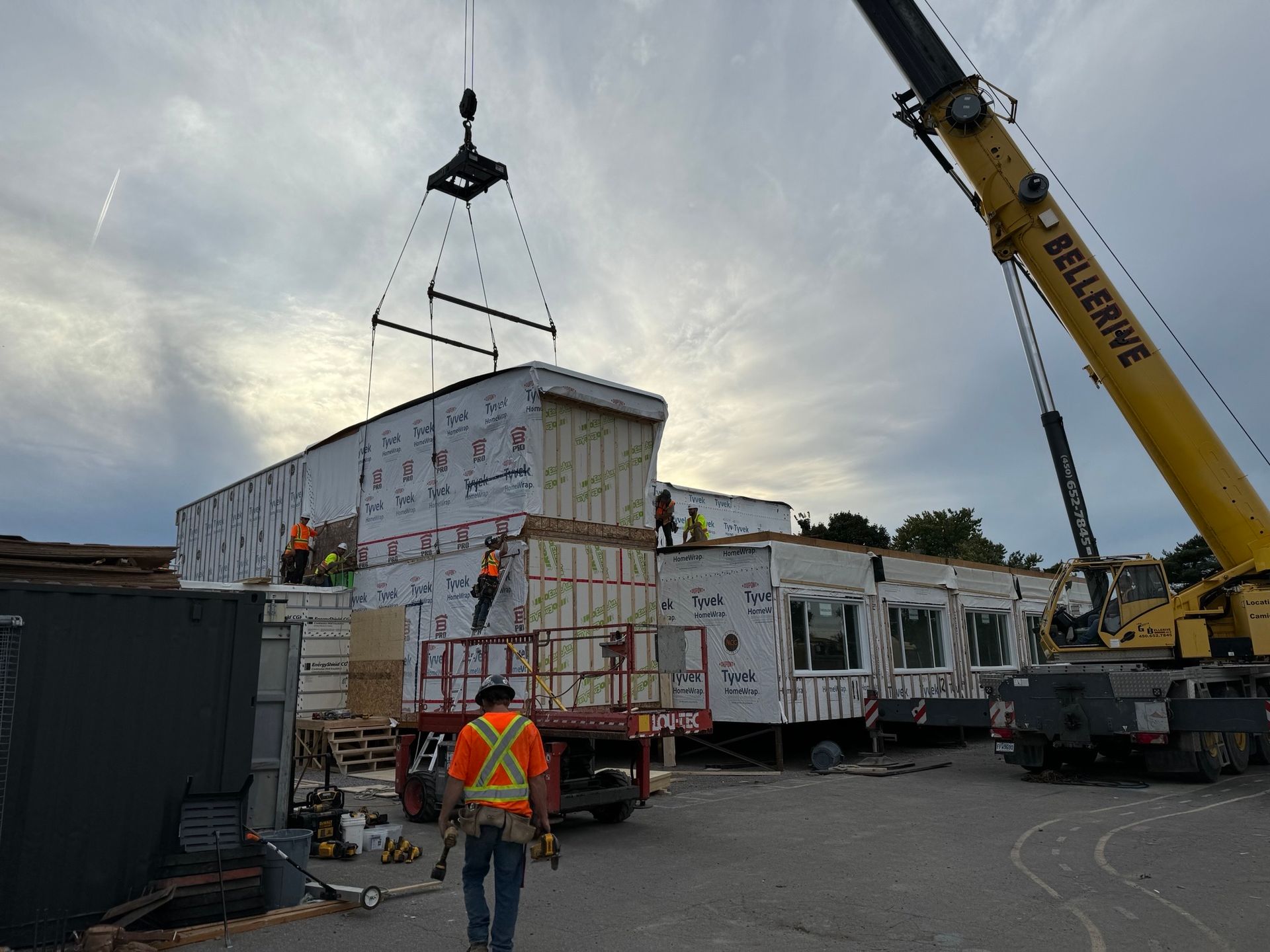 A crane is lifting a building in a parking lot.