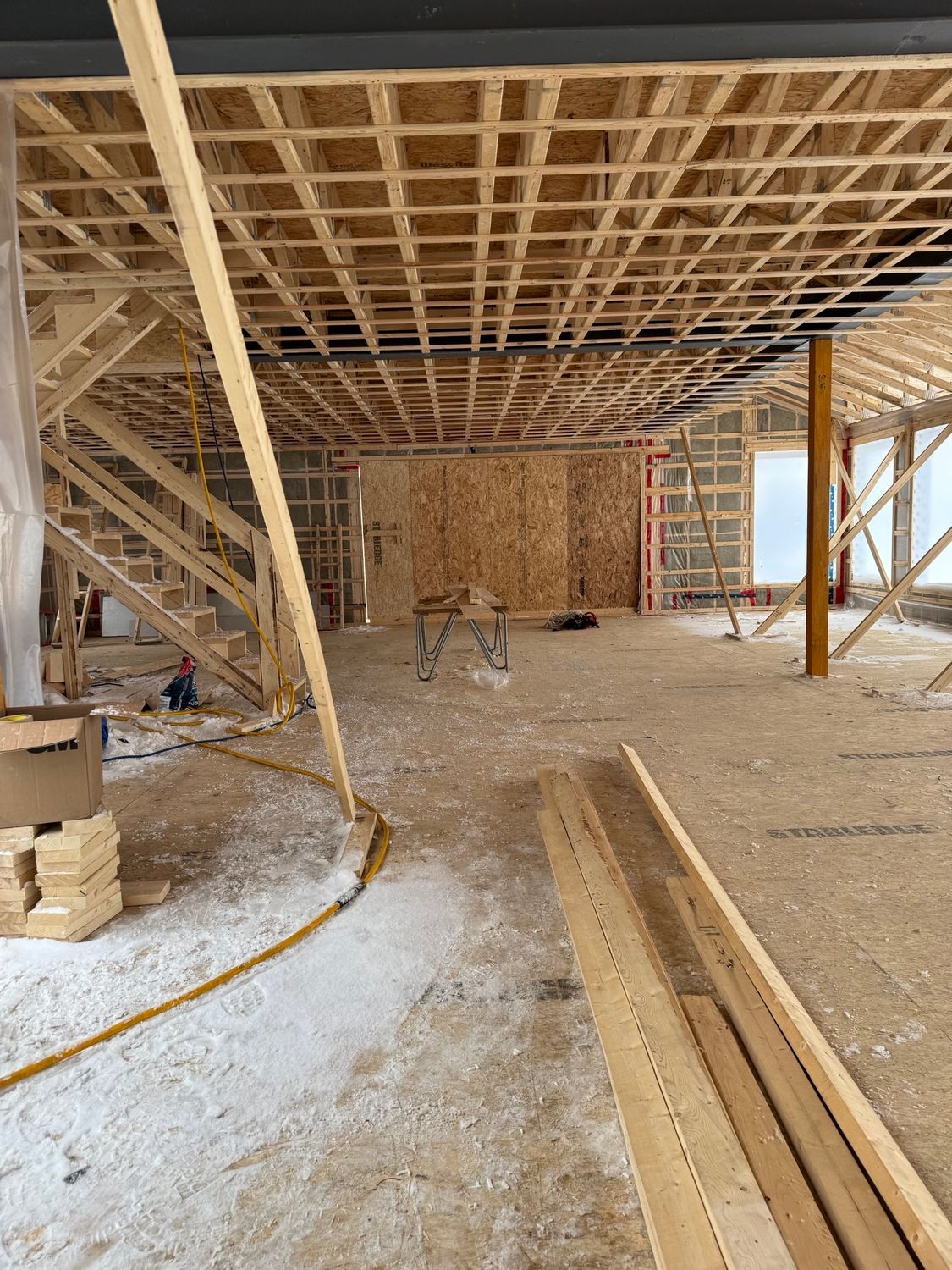A large room under construction with wooden beams and stairs.