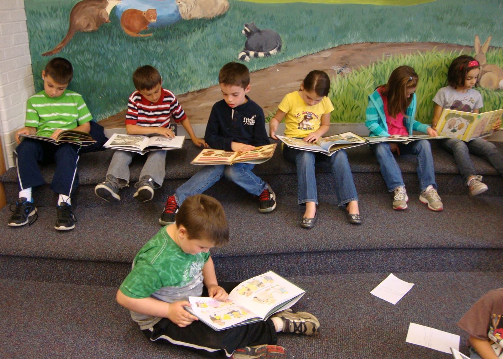 A group of children are sitting on the floor reading books