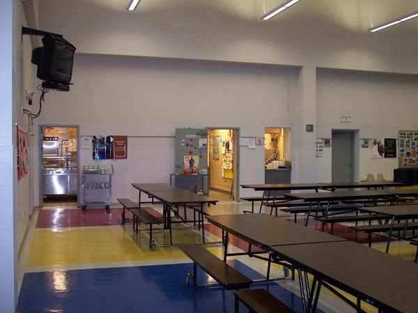 The inside of a school cafeteria with tables and benches