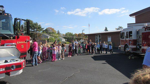 A group of children are standing in front of a fire truck with the number 5 on it