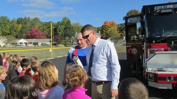 A group of children are standing in front of a fire truck.