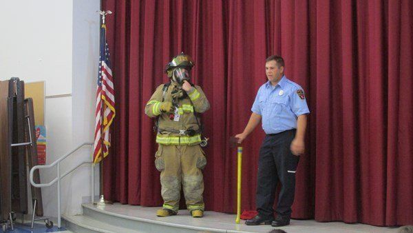 A firefighter and a police officer are standing on a stage in front of an american flag.