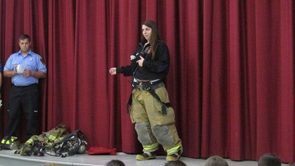 A woman in a fireman 's uniform is standing on a stage.