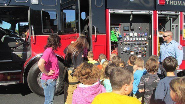 A group of children are standing in front of a fire truck.