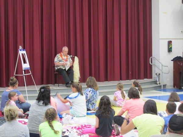 A man is reading a book to a group of children sitting on the floor.