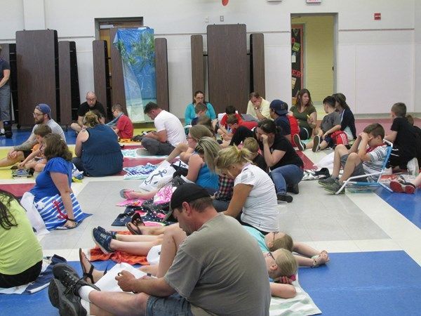 A group of people are sitting on the floor in a gym