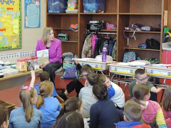 A woman is reading a book to a group of children in a classroom